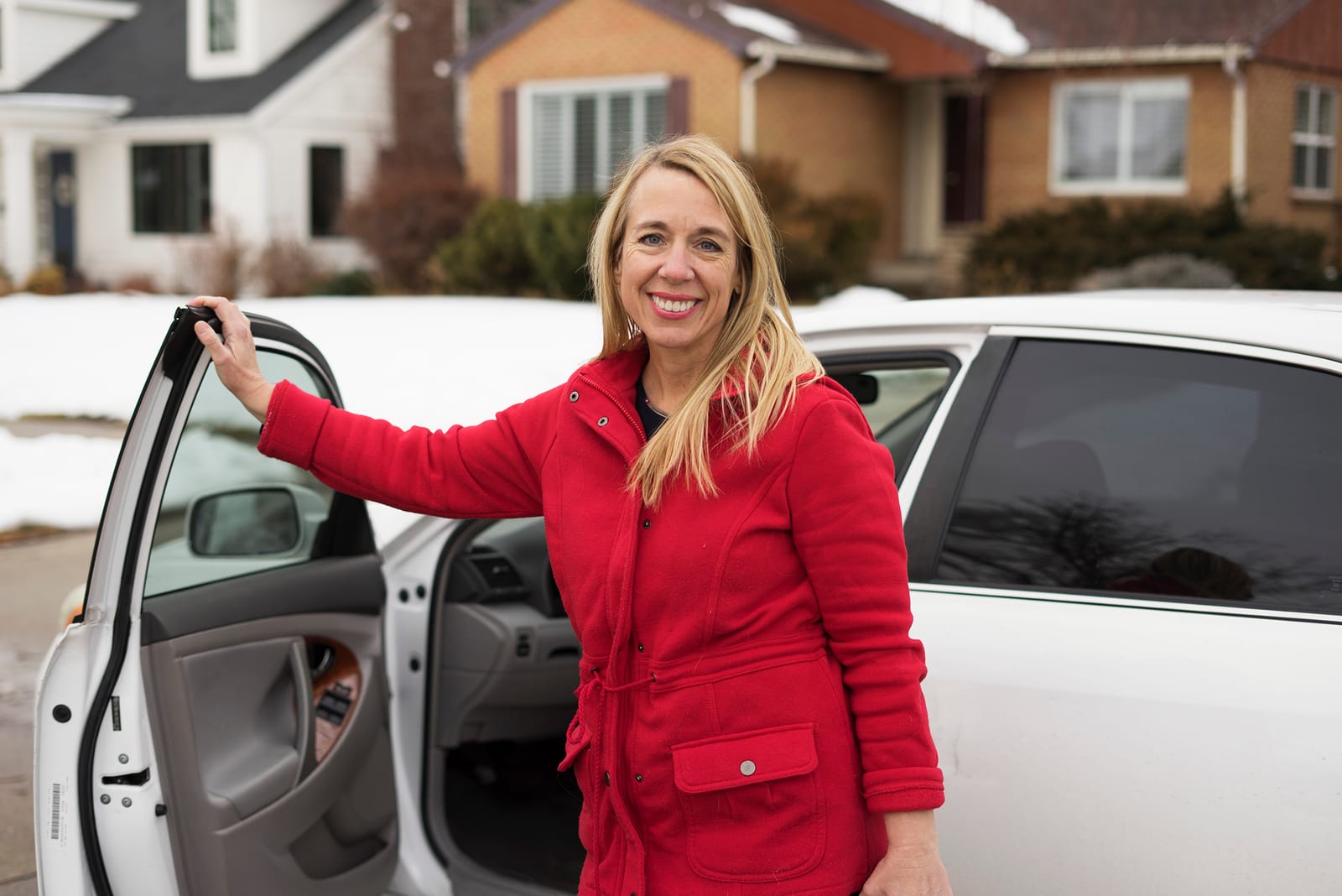 Julie stepping out of her car on a snowy Utah street, on her way to a home visit