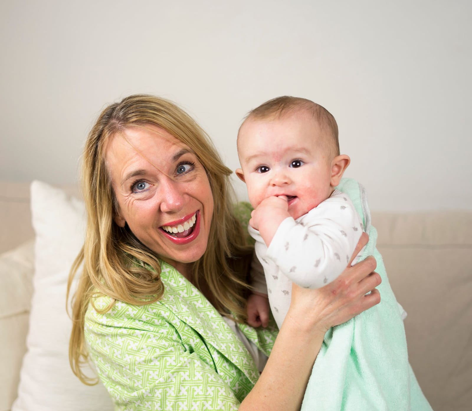 Julie laughing while she holds a smiling baby against her shoulder