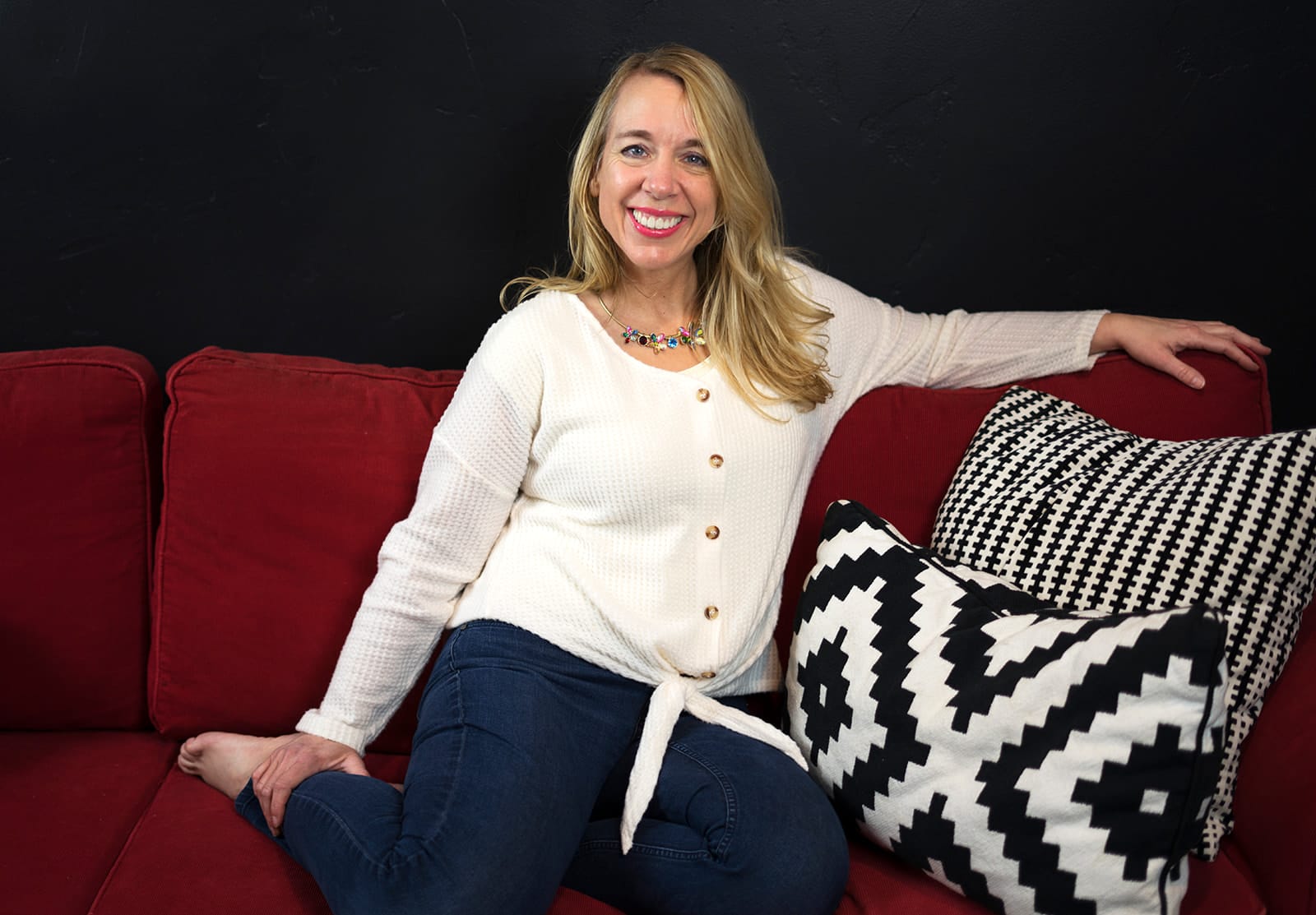 Julie Johnson smiling, seated on a red sofa