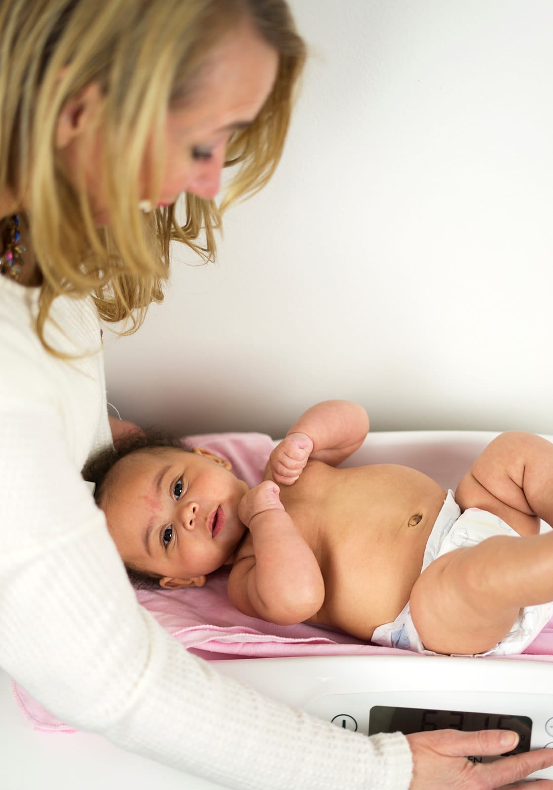 Julie steadying a baby on an infant scale during a weight check